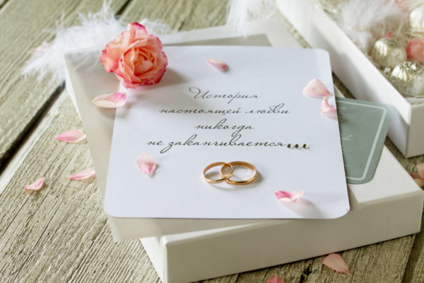 Two Golden Wedding Rings, box of chocolates and a wedding invitation, an inscription that the story of true love never ends. Copy space.